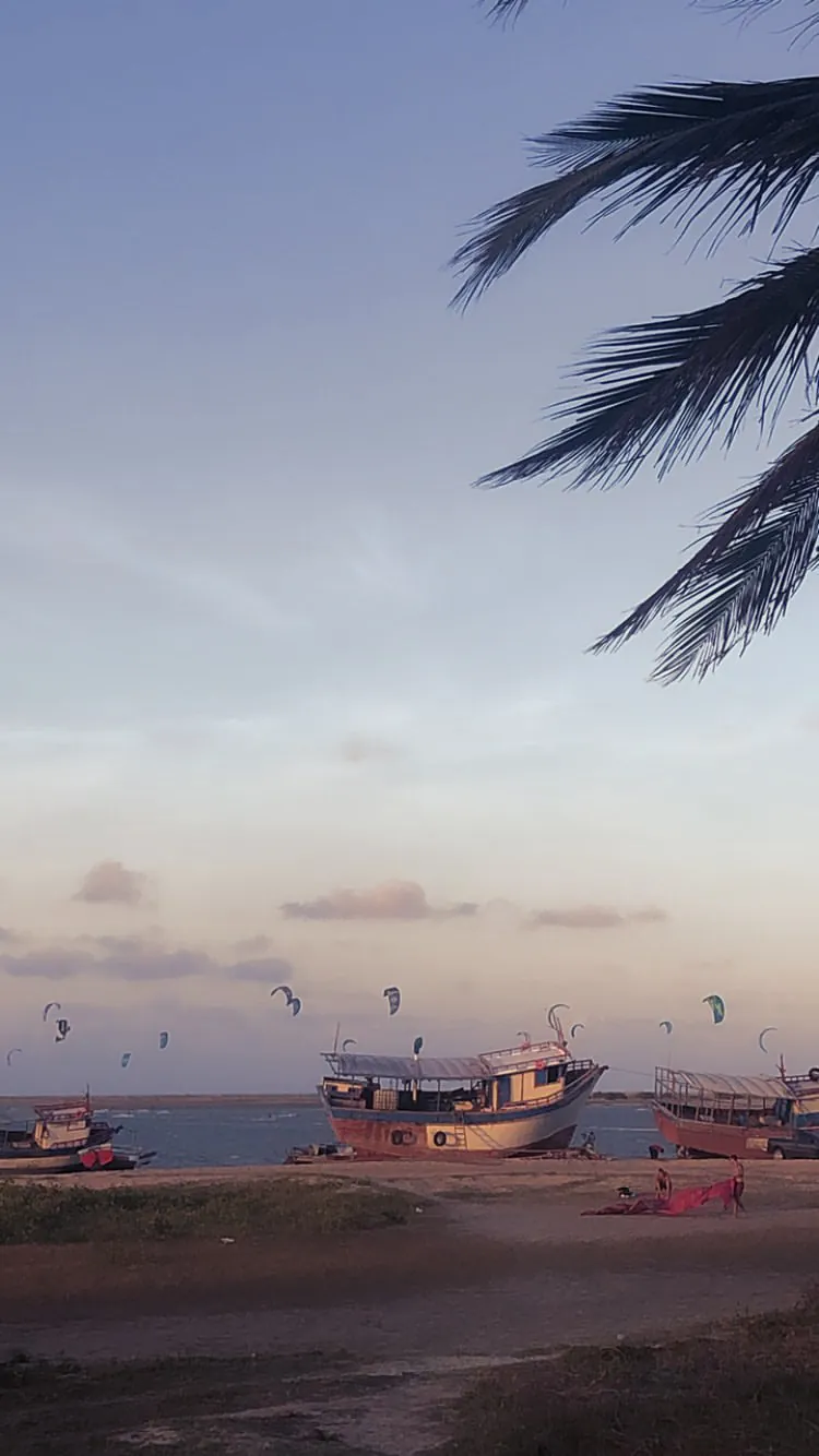 Kitesurfista velejando na água plana da Ilha do Guajirú com jangada ao fundo