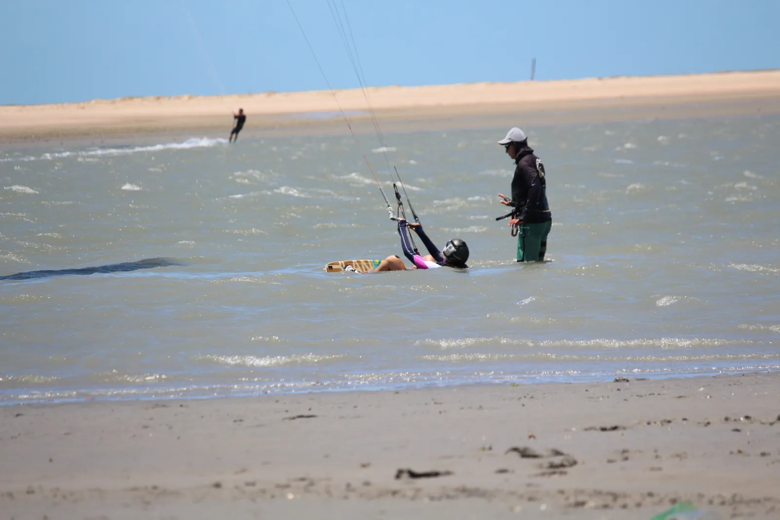 Kitesurfista navegando na água plana do braço de mar com pipa no céu azul na Ilha do Guajirú