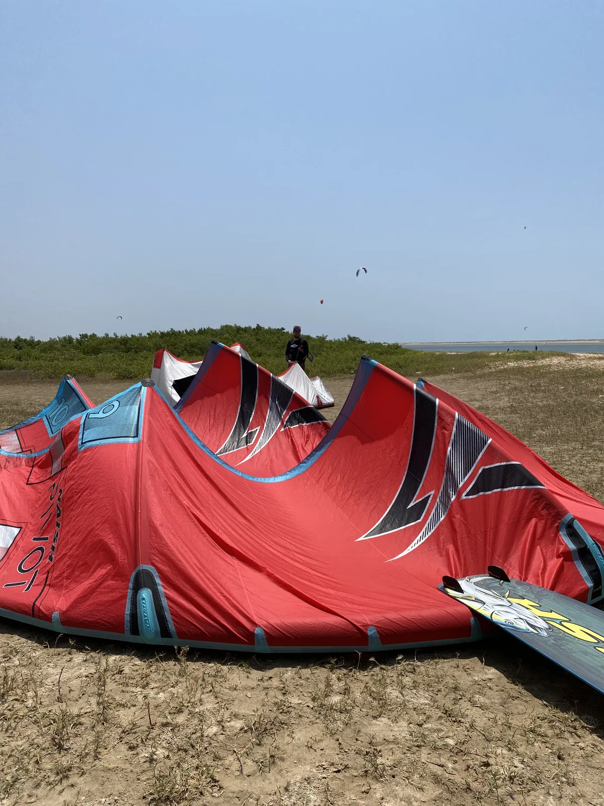 Kite vermelho da Naish apoiado na areia da praia da Ilha do Guajirú