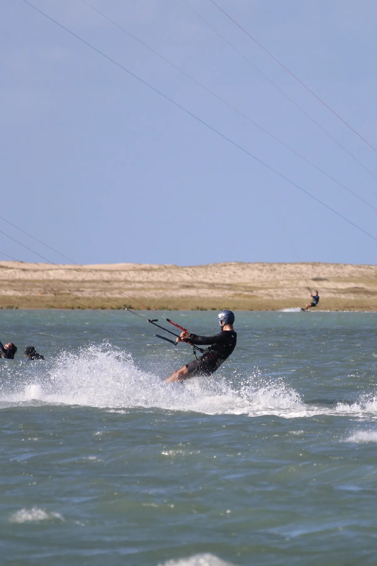 Kitesurfista saltando com spray na água plana da Ilha do Guajirú