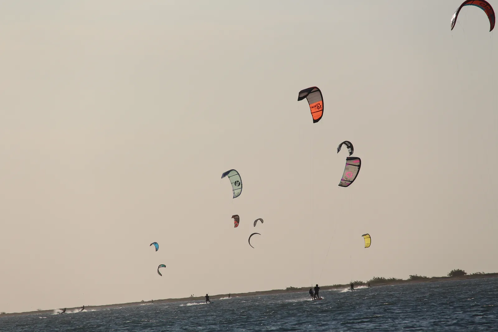 Pipas de kitesurf coloridas sobre o braço de mar da Ilha do Guajirú ao entardecer