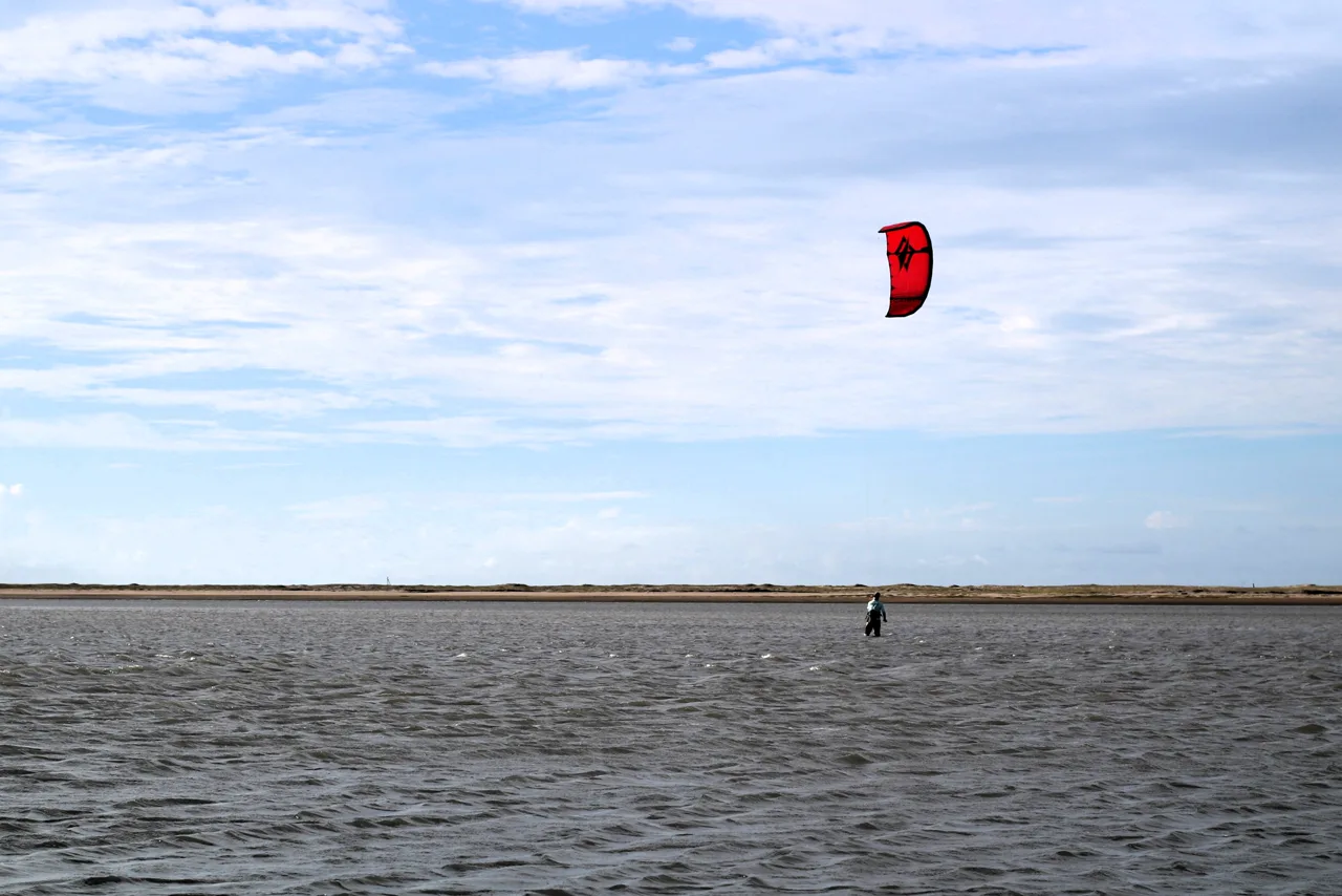 Kitesurf no braço de mar raso e plano da Ilha do Guajirú, com kite Naish e horizonte aberto
